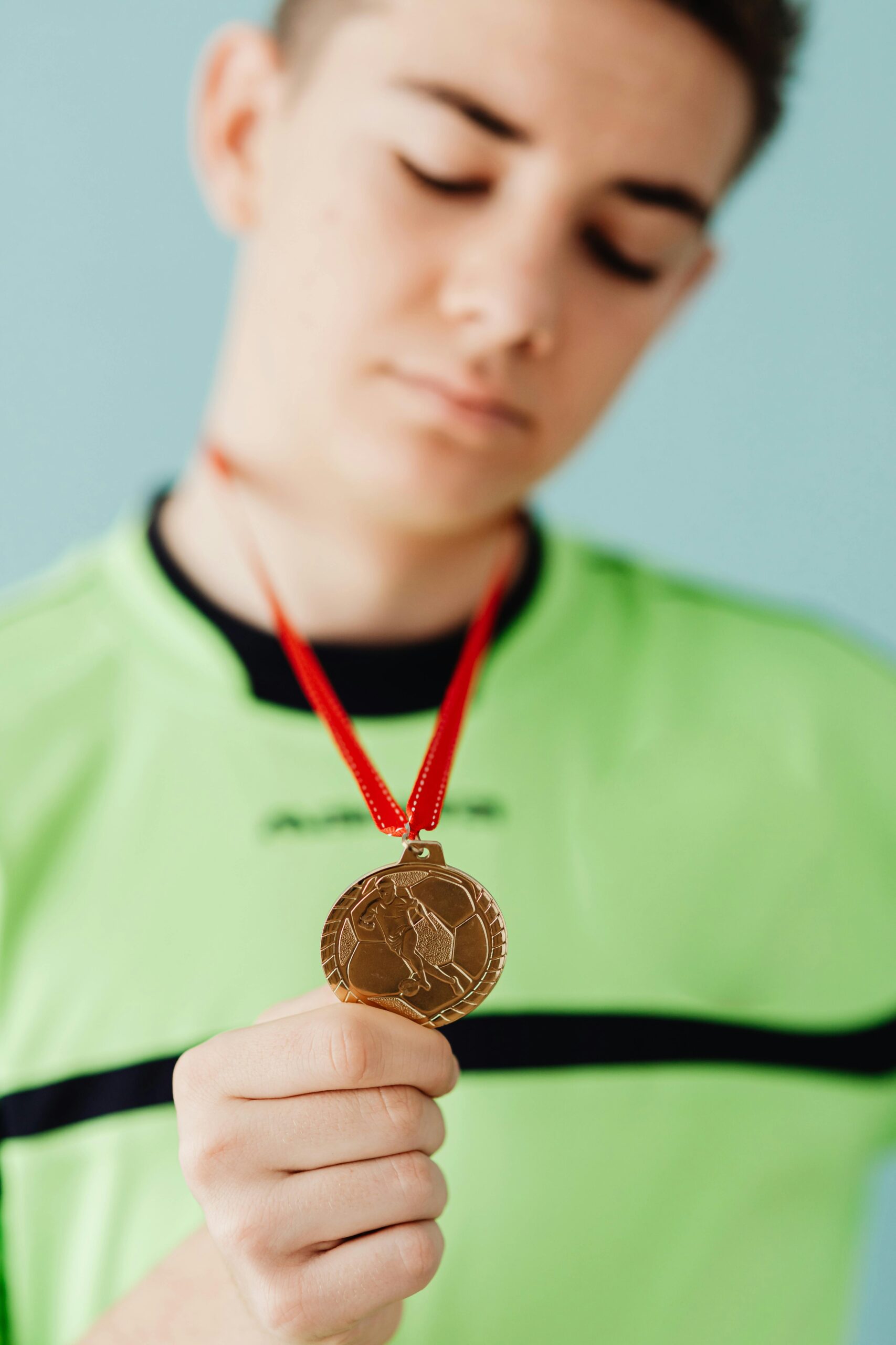 Portrait of a young athlete proudly displaying a gold medal, symbolizing victory and achievement.